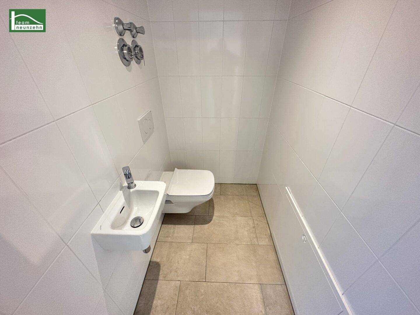 Separates WC mit wandhängender Toilette und kleinem Handwaschbecken.