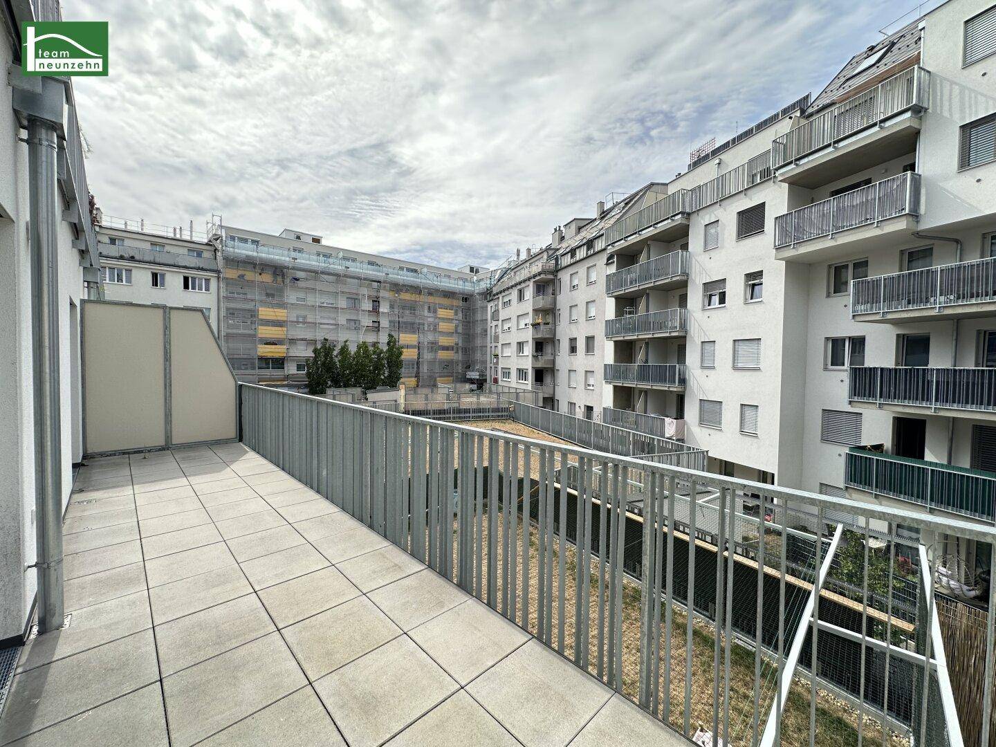 Große Außenterrasse mit Fliesenboden und Blick auf die umliegenden Wohngebäude.