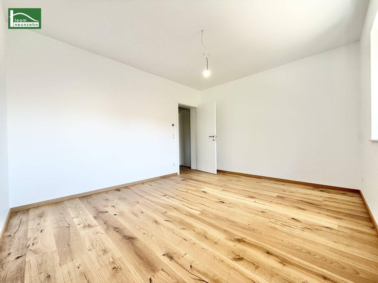 Helles Schlafzimmer mit neuem Echtholzparkett und weiß gestrichenen Wänden.