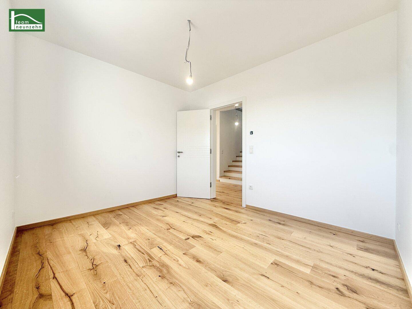 Helles Schlafzimmer mit Holzboden und weiß gestrichenen Wänden, bereit zur Einrichtung.