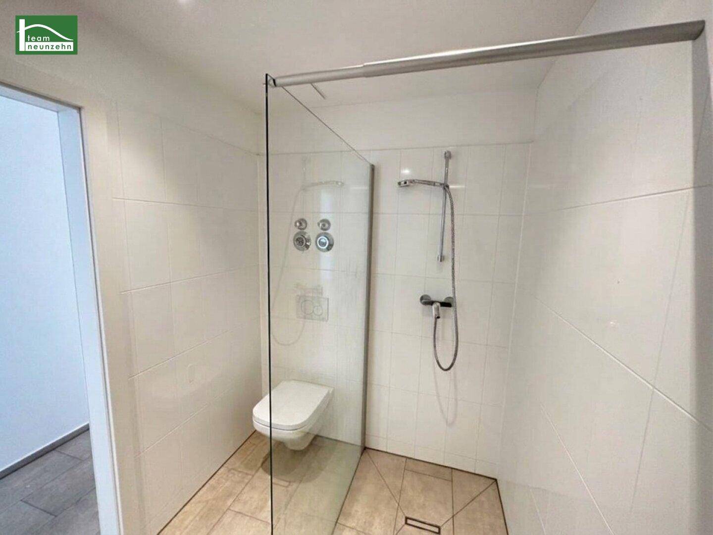 Helles Badezimmer mit begehbarer Dusche, Glasabtrennung und wandhängendem WC.