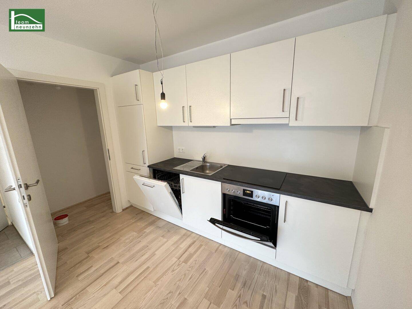 Funktionale Einbauküche mit weißen Schränken, integriertem Geschirrspüler und Backofen.