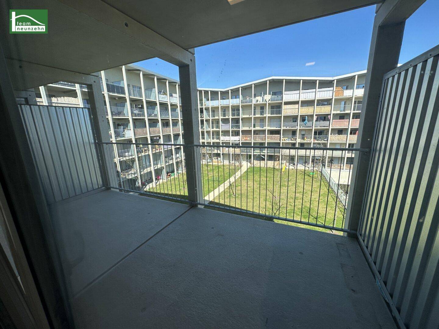 Geräumiger Balkon mit Blick auf den grünen Innenhof und die umliegenden Wohngebäude.