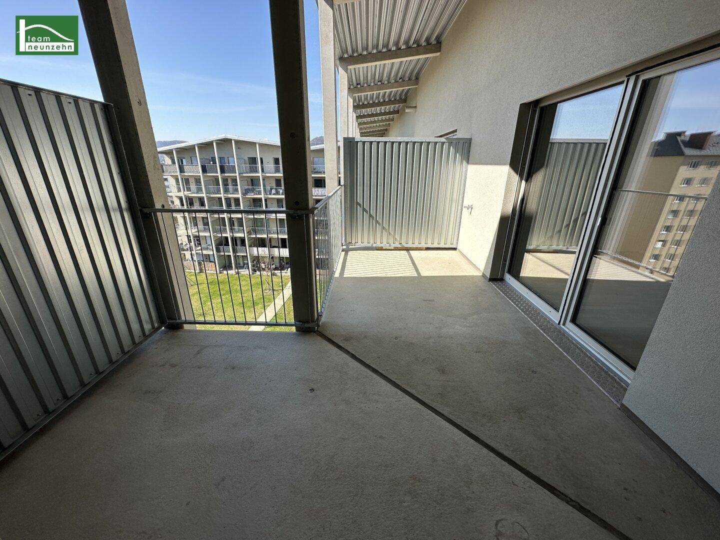 Geräumiger Balkon mit Betonboden und Metallgeländer, bietet Platz für Entspannung im Freien.