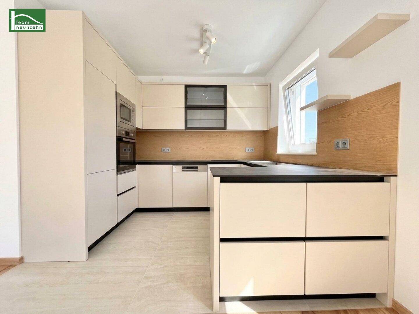 Moderne Einbauküche in Beige mit integrierten Geräten und dunkler Arbeitsplatte.