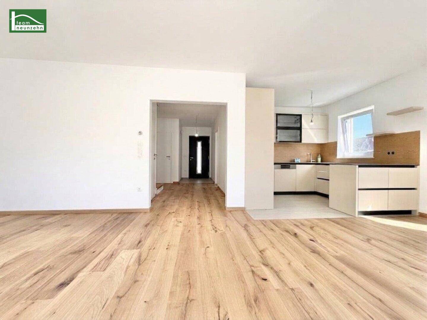 Offener Wohn- und Essbereich mit Holzboden und integrierter moderner Küche.