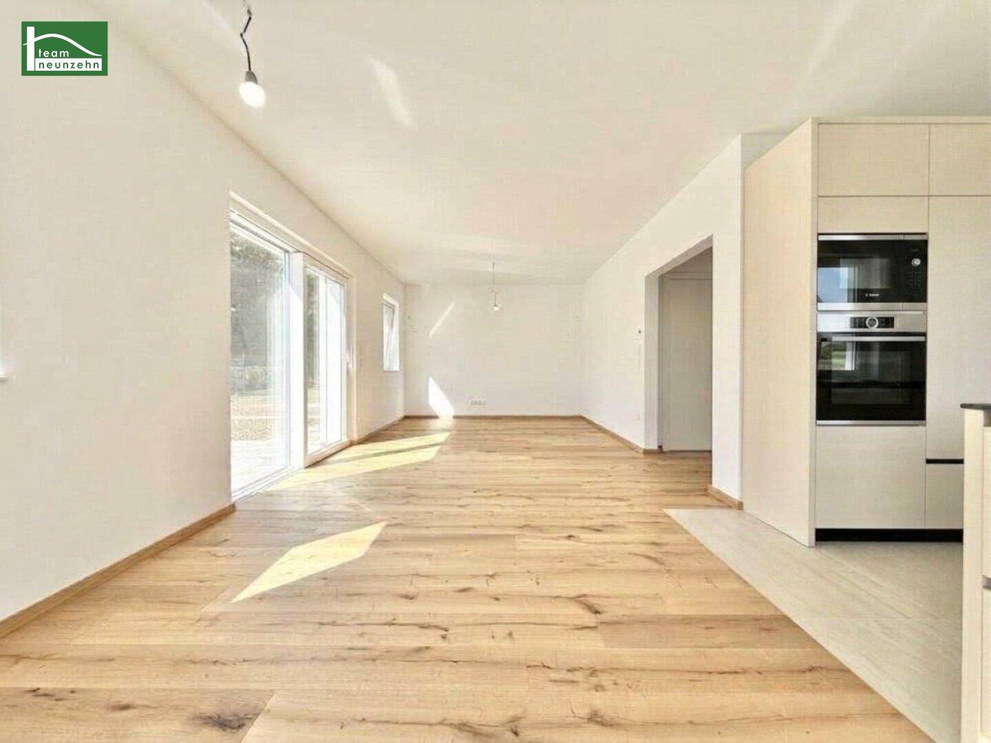 Geräumiger offener Wohnbereich mit Holzboden und integrierter moderner Küchenzeile.