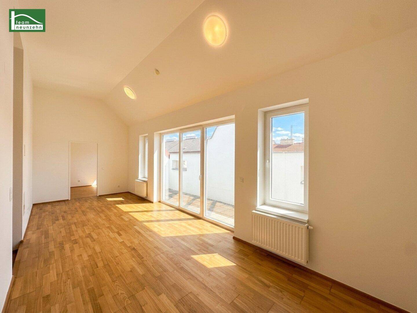 Großes, lichtdurchflutetes Wohnzimmer mit Parkettboden und breiter Schiebetür zur Terrasse.