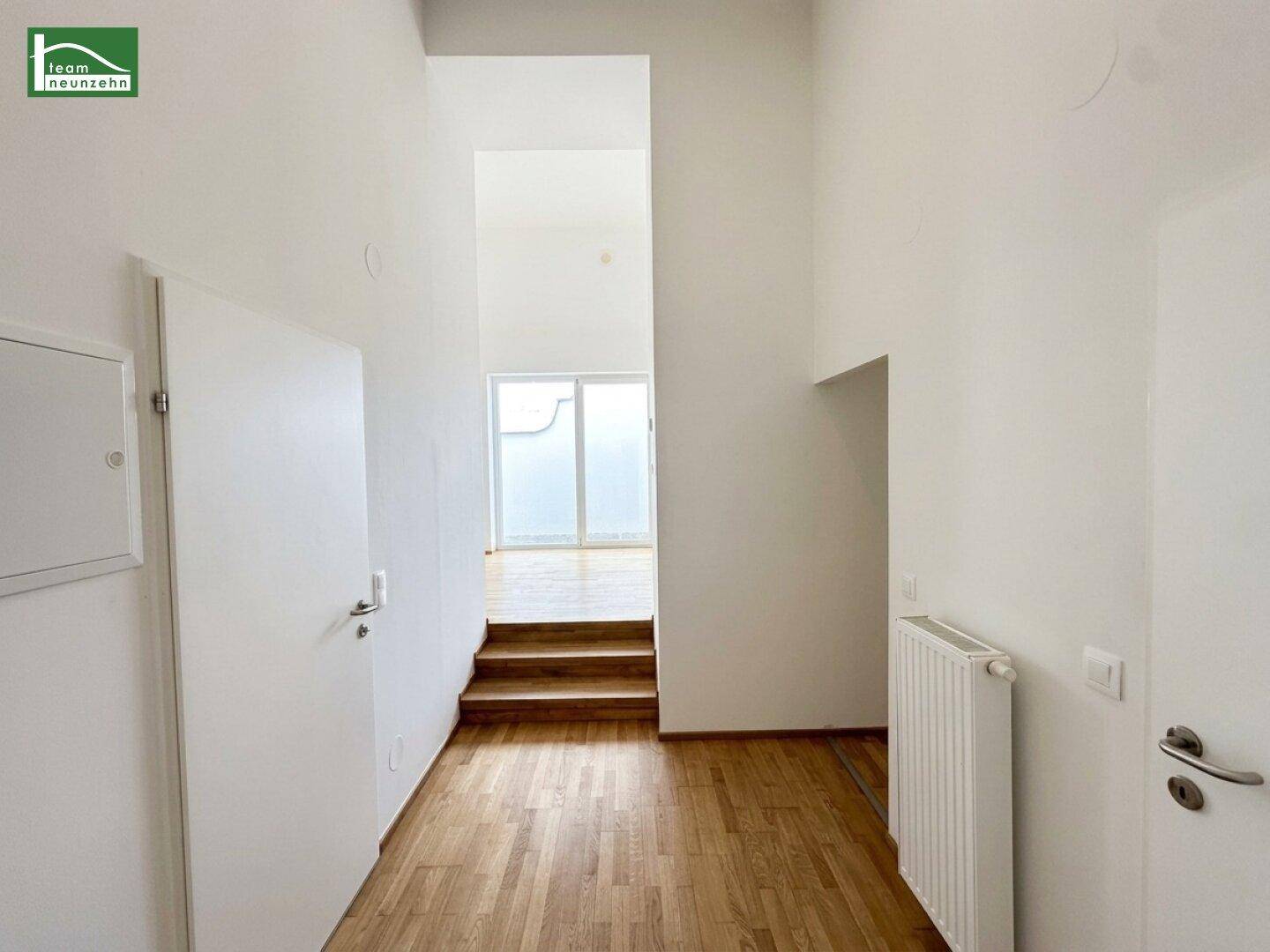 Heller Flur mit Holztreppe, Parkettboden und Zugang zu weiteren Räumen im Dachgeschoss.
