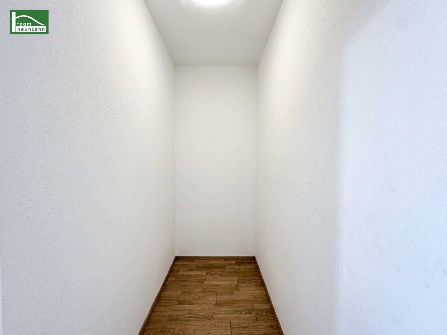 Kleiner, leerer Abstellraum mit Holzboden und weißen Wänden, ideal für Lagerung.