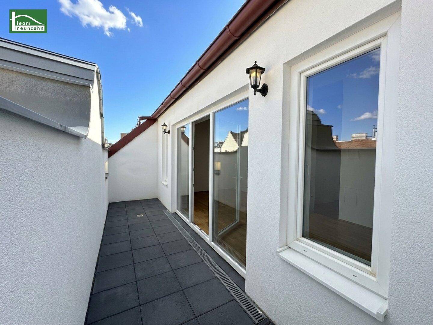 Lange Dachterrasse mit Fliesenboden und Zugang durch große Schiebetüren zum Innenbereich.