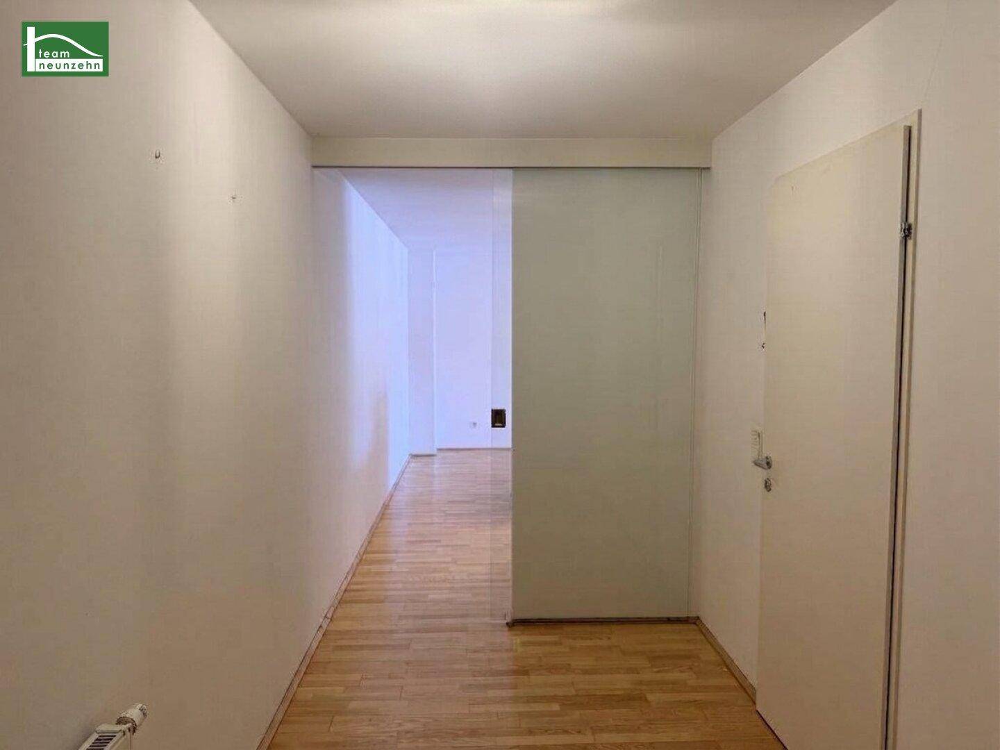Heller Flur mit Parkettboden und einer modernen Schiebetür aus Milchglas.