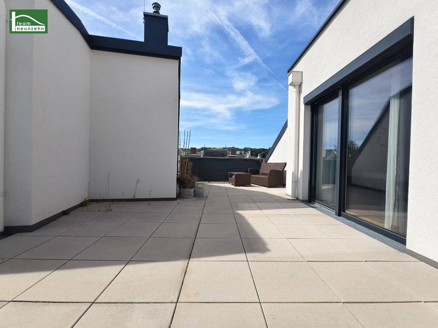Sonniger Terrassenbereich mit großen Schiebetüren und bequemen Outdoor-Möbeln.