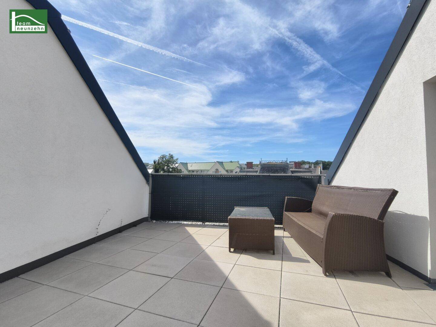 Gemütliche Dachterrasse mit Outdoor-Sofa und Blick auf die Dächer der Stadt.
