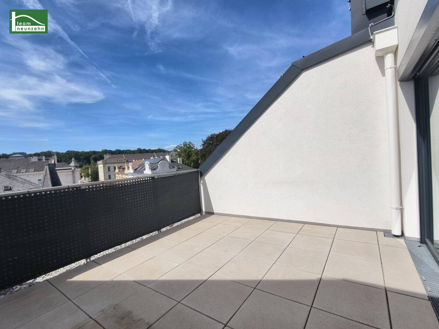 Sonniger Terrassenbereich mit Fliesenboden und weitem Blick über die Stadt.