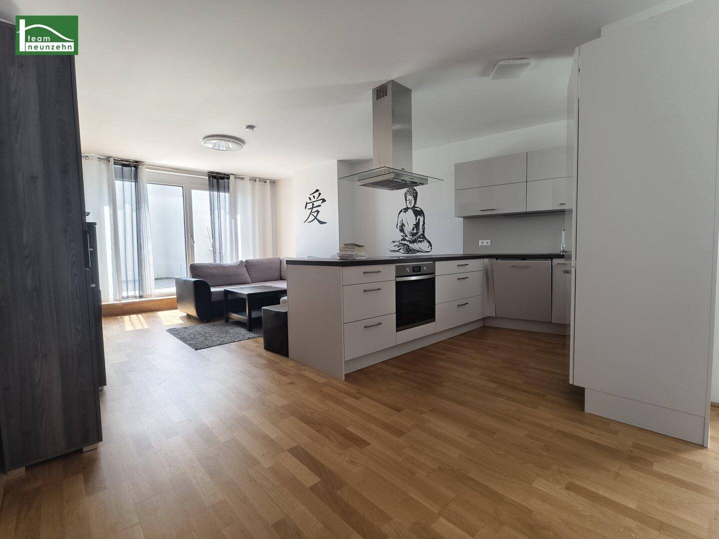 Moderne offene Küche mit Kochinsel und integriertem Backofen, verbunden mit dem Wohnbereich.