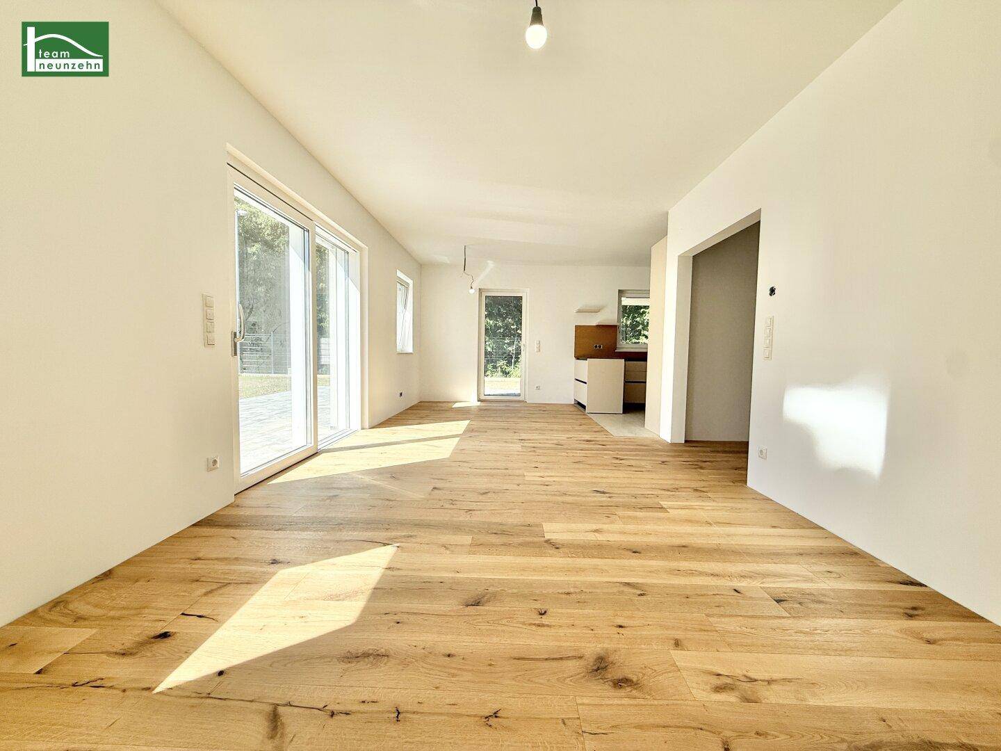Lichtdurchfluteter Wohnbereich mit Zugang zum Garten und durchgehendem Holzboden.