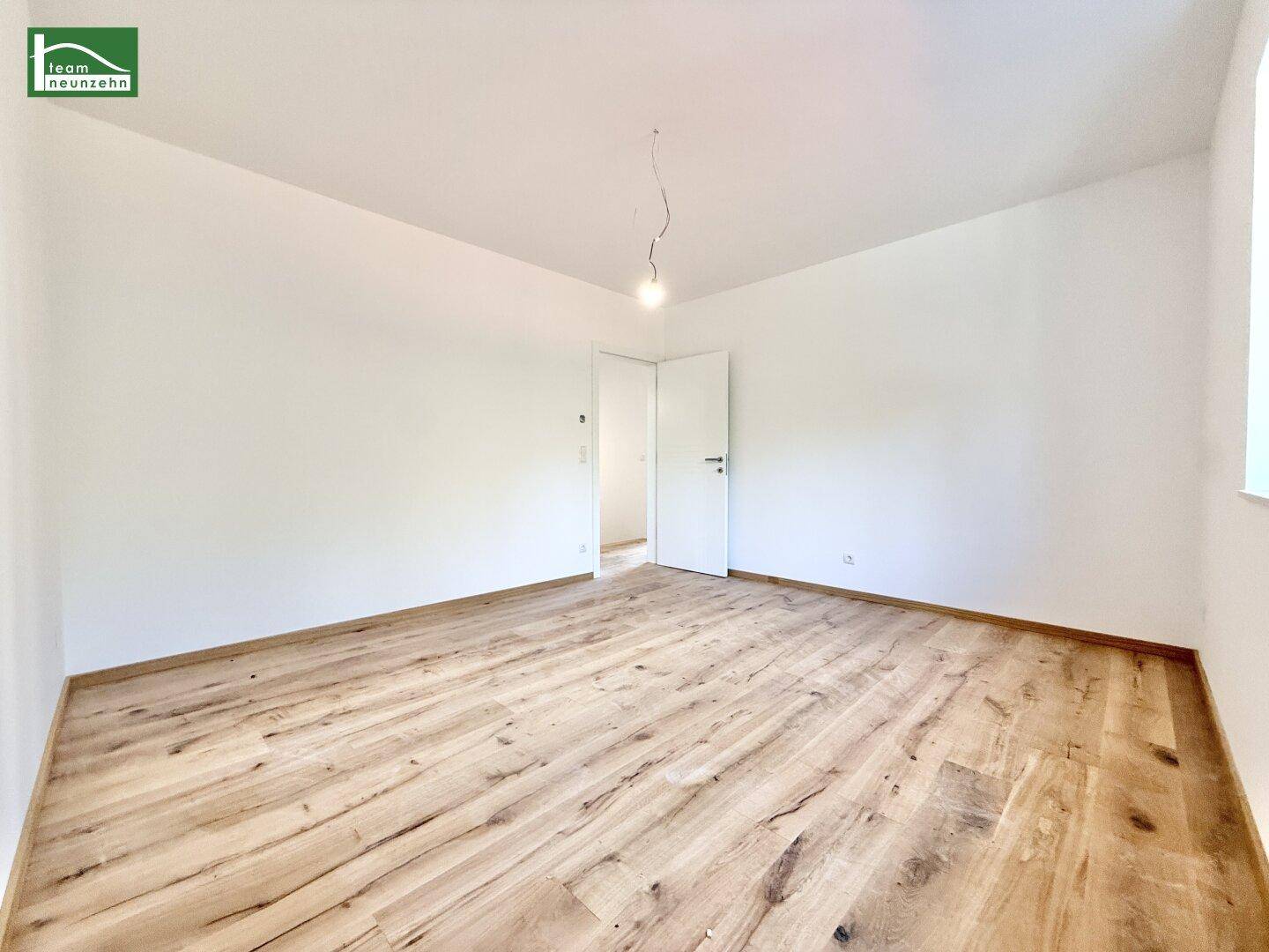 Helles Schlafzimmer mit hochwertigem Holzboden und weiß gestrichenen Wänden.