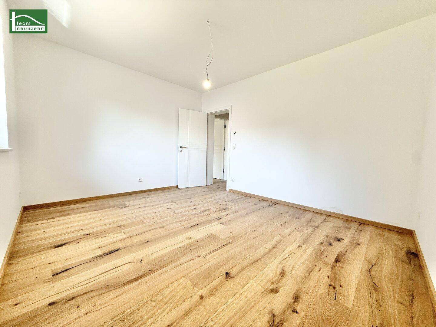 Helles Schlafzimmer mit Holzboden und Zugang zu weiteren Räumen.