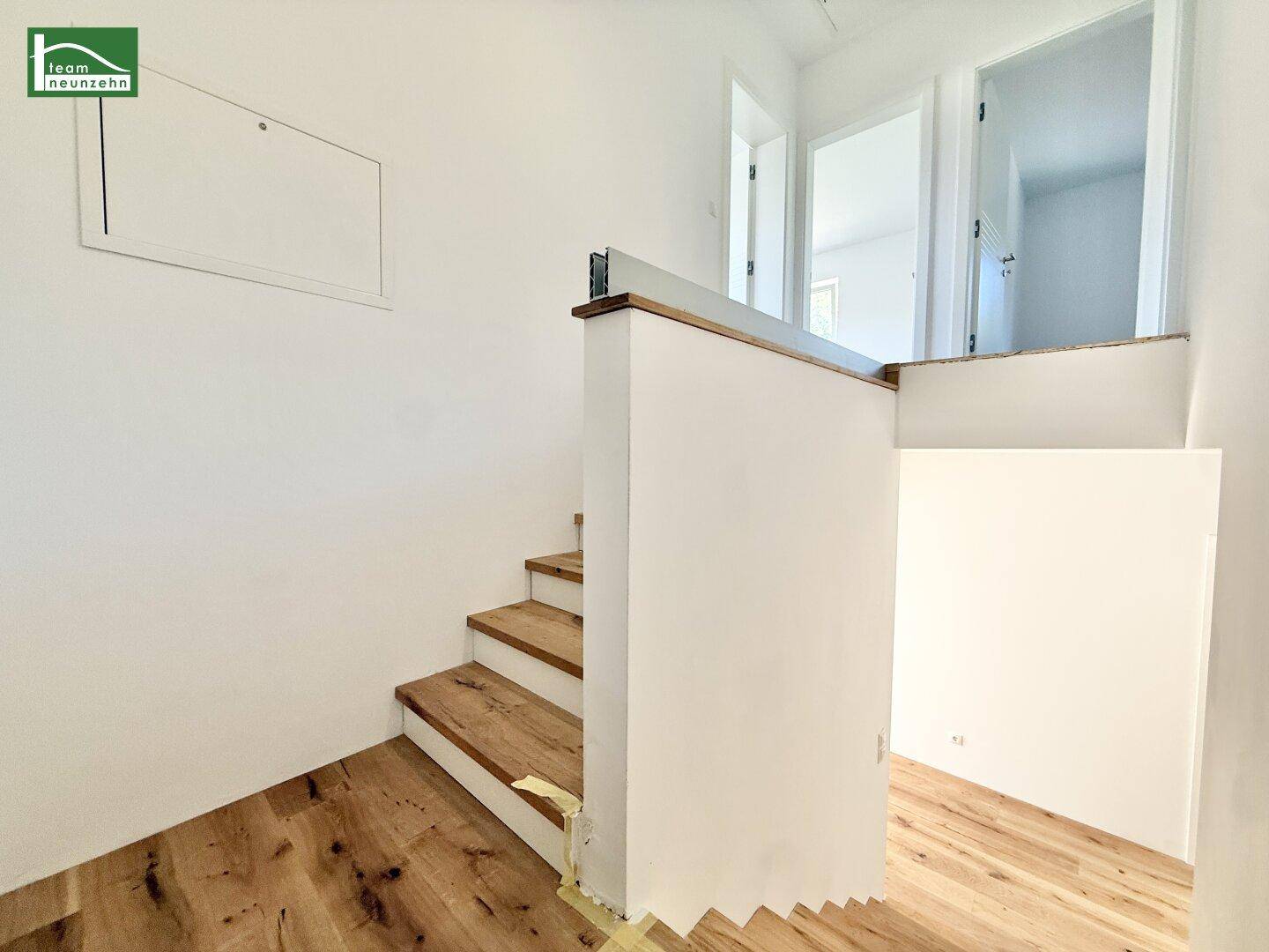 Heller Flur mit Holztreppe, die in die oberen Etagen führt.