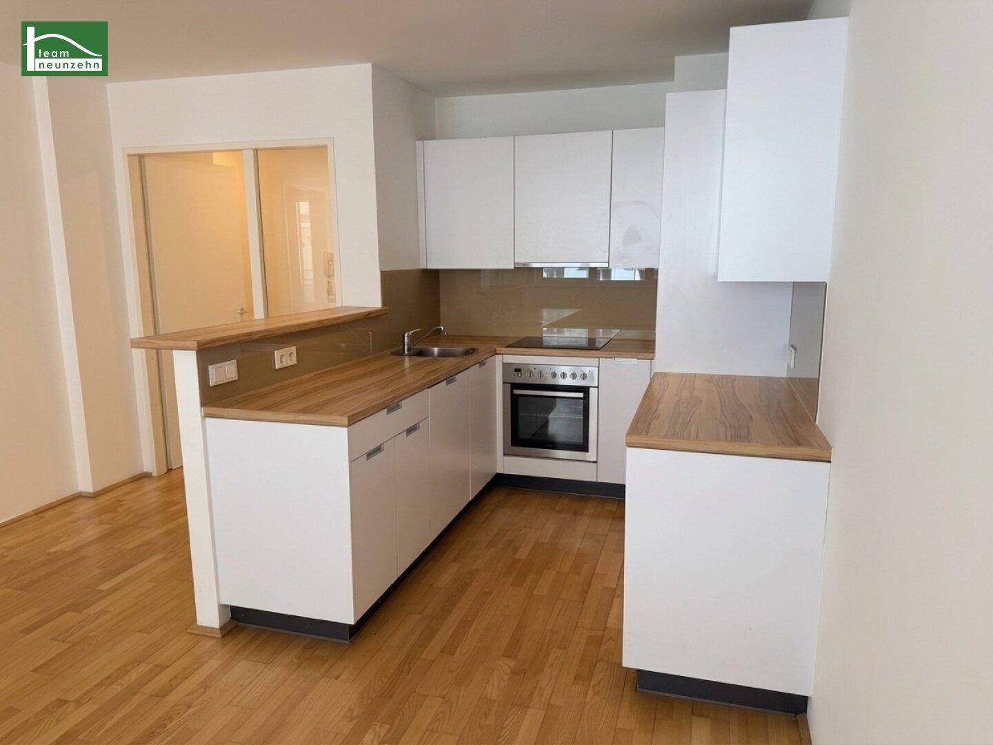 Moderne Einbauküche mit weißen Schränken, Holz-Arbeitsplatten und integriertem Backofen.