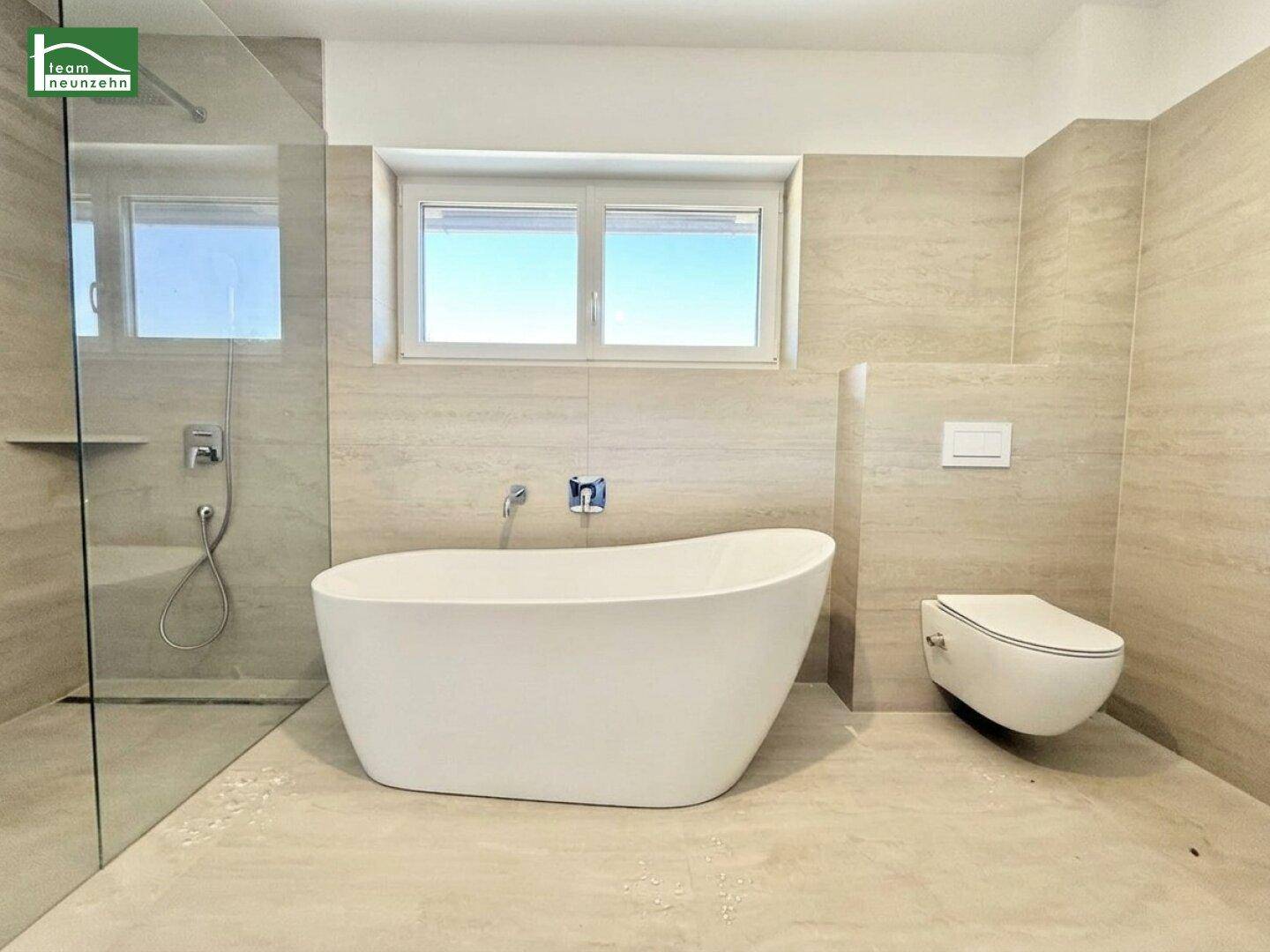 Modernes Badezimmer mit freistehender Badewanne, ebenerdiger Dusche und Wand-WC.