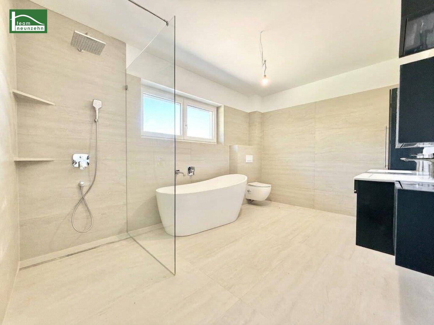Geräumiges Badezimmer mit moderner Ausstattung, freistehender Wanne und großer Dusche.