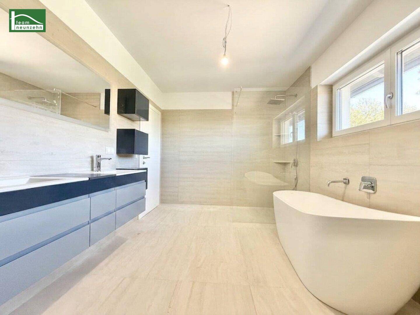 Elegantes Badezimmer mit Doppelwaschbecken, freistehender Badewanne und großer Dusche.