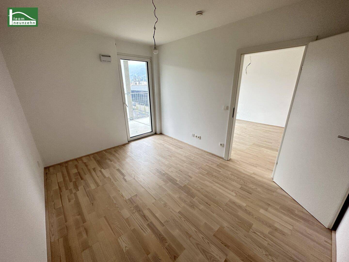 Heller, unmöblierter Raum mit Holzboden und Zugang zu einem Balkon, ideal als Schlafzimmer.