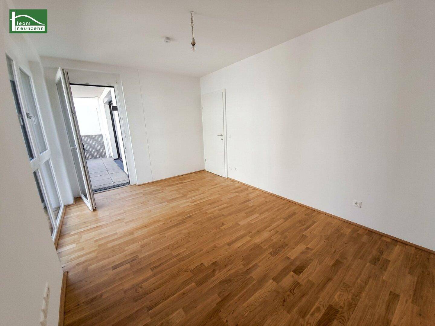 Lichtdurchflutetes Schlafzimmer mit Parkettboden und direktem Zugang zum Balkon.
