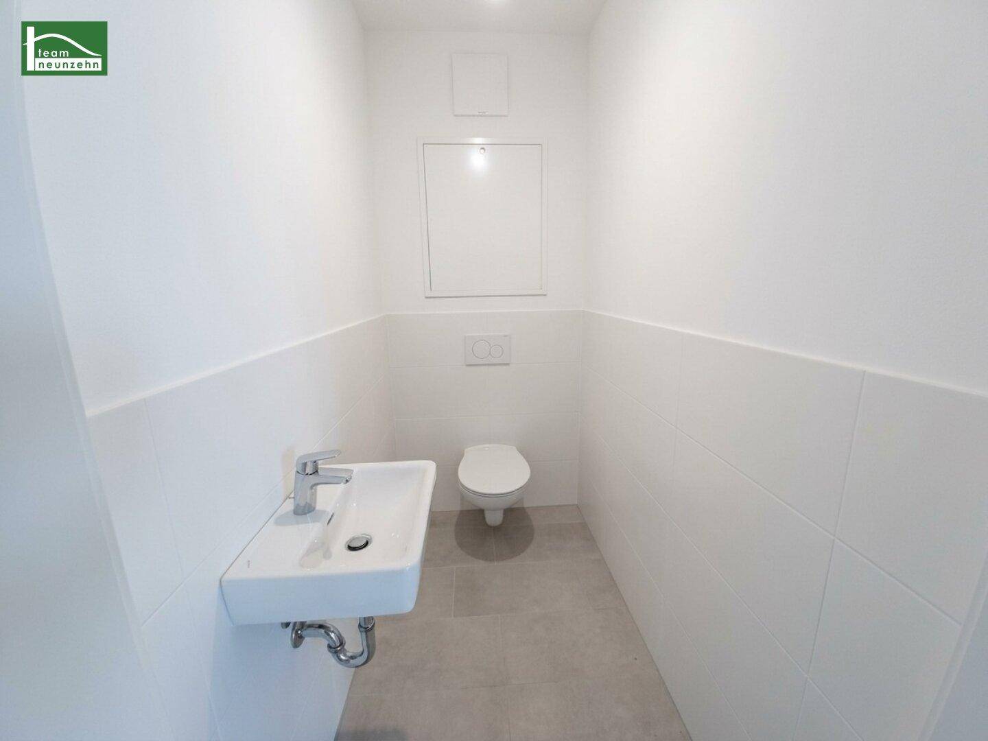 Separates Gäste-WC mit wandhängendem WC und kleinem Waschbecken.