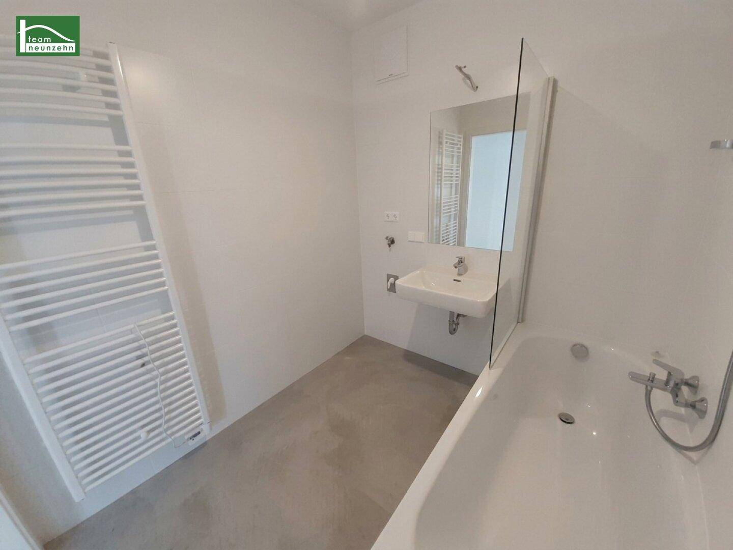 Modernes Badezimmer mit Badewanne, Waschbecken und beheiztem Handtuchhalter.