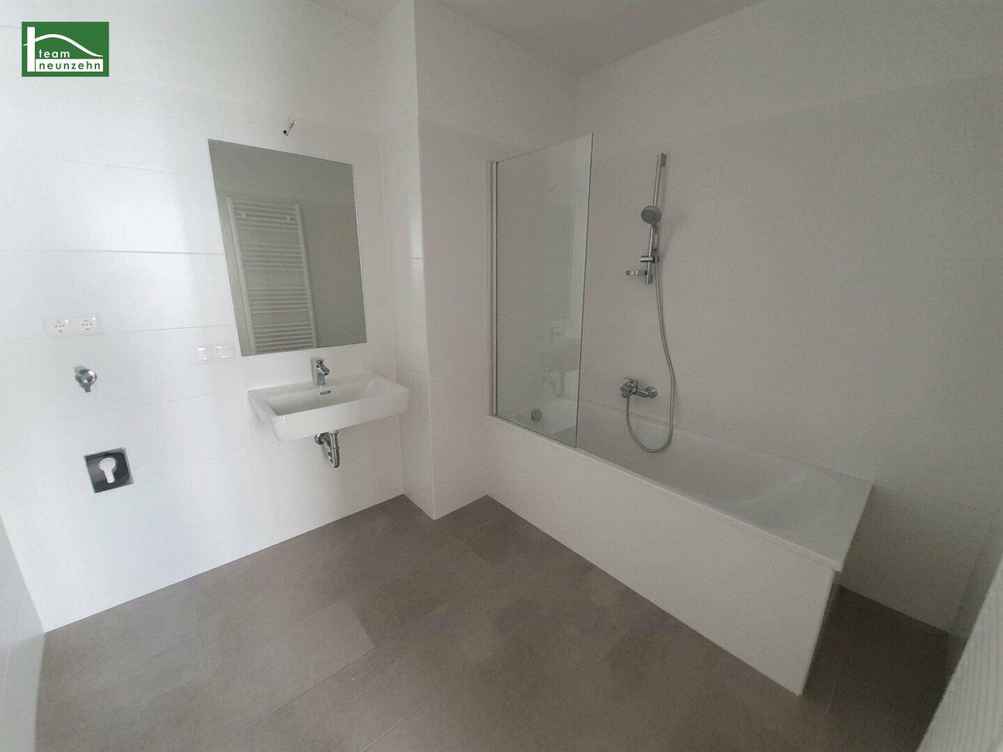 Modernes Badezimmer mit Badewanne, Einzelwaschbecken und beheiztem Handtuchhalter.