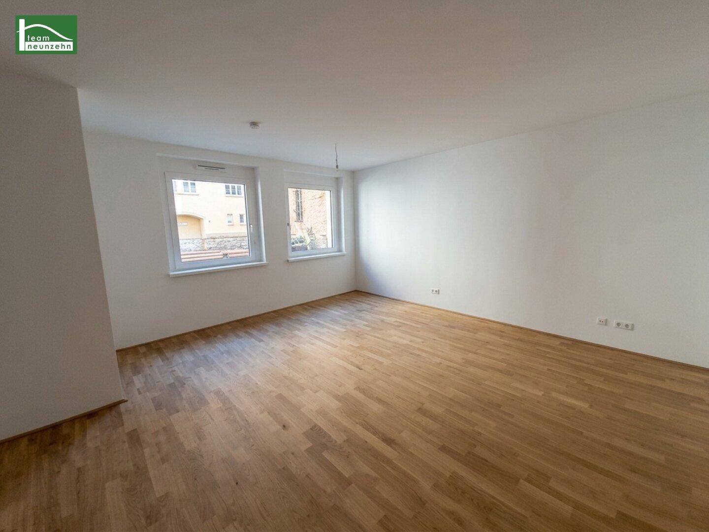 Heller, leerer Raum mit Parkettboden und zwei Fenstern, bereit zur individuellen Gestaltung.