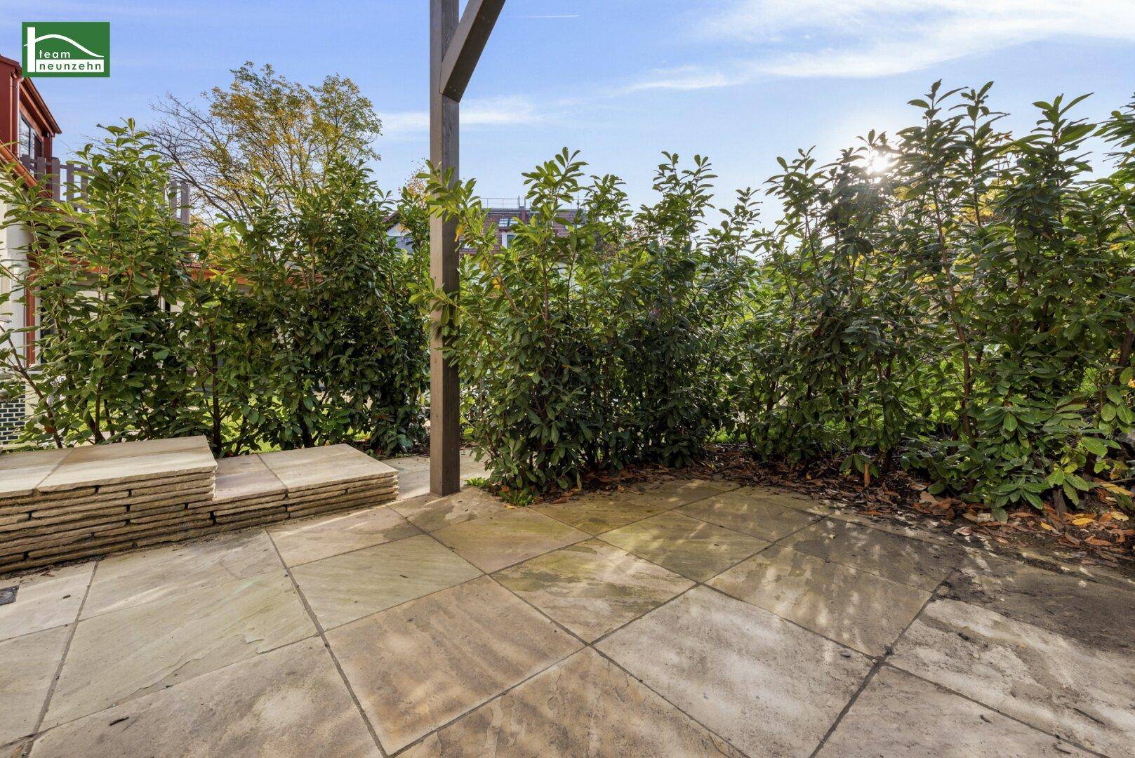 Gepflasterte Terrasse umgeben von grünen Hecken, ideal für entspannte Stunden im Freien mit viel Sonnenlicht.