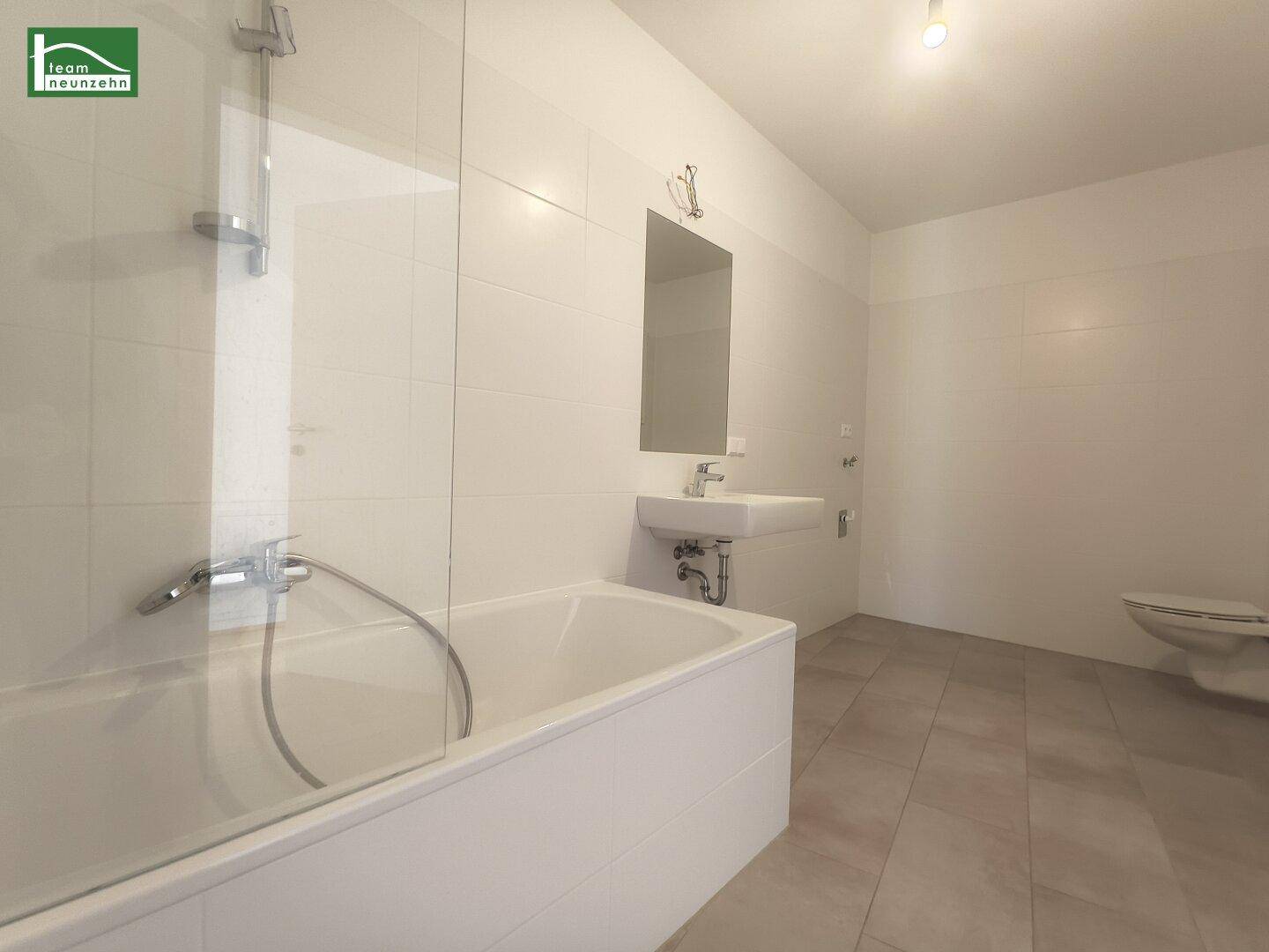 Modernes Badezimmer mit Badewanne, Duschabtrennung, Einzelwaschbecken und Wand-WC.