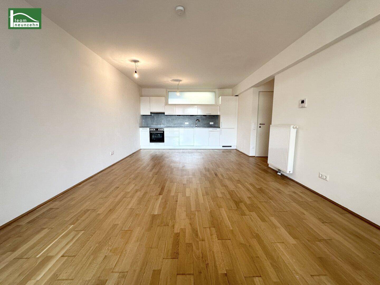 Offener Küchenbereich mit modernen weißen Einbauschränken und Holzboden.