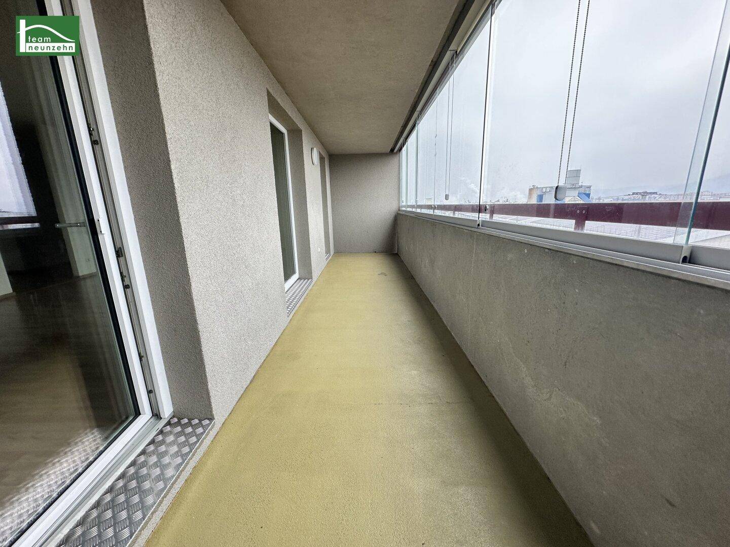 Verglaste Loggia mit gelbem Boden und Blick auf die Umgebung, ideal für Entspannung.