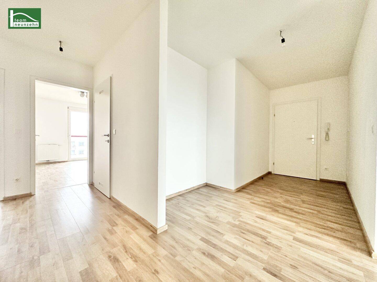 Heller Flurbereich mit Laminatboden und weißen Wänden, der zu weiteren Räumen führt.