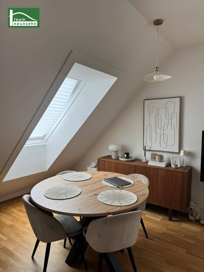 Heller Essbereich im Dachgeschoss mit Holztisch, Dachfenster und moderner Dekoration.
