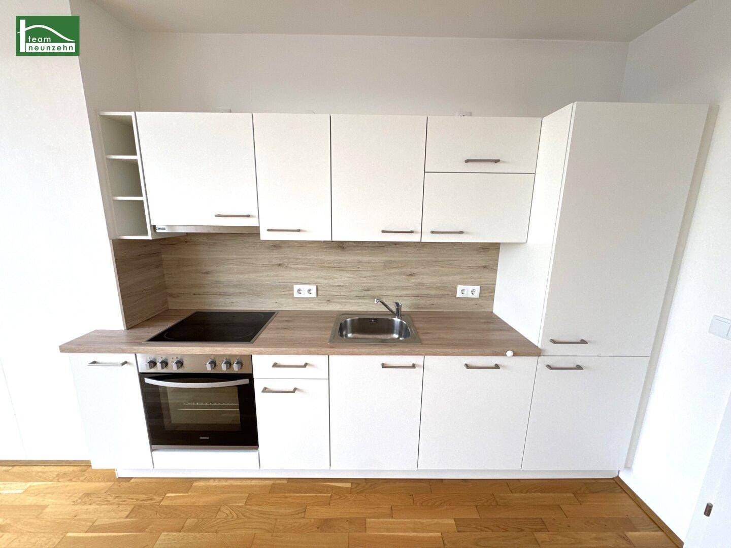 Moderne Einbauküche mit weißen Fronten, Holzoptik-Arbeitsplatte und integrierten Geräten.