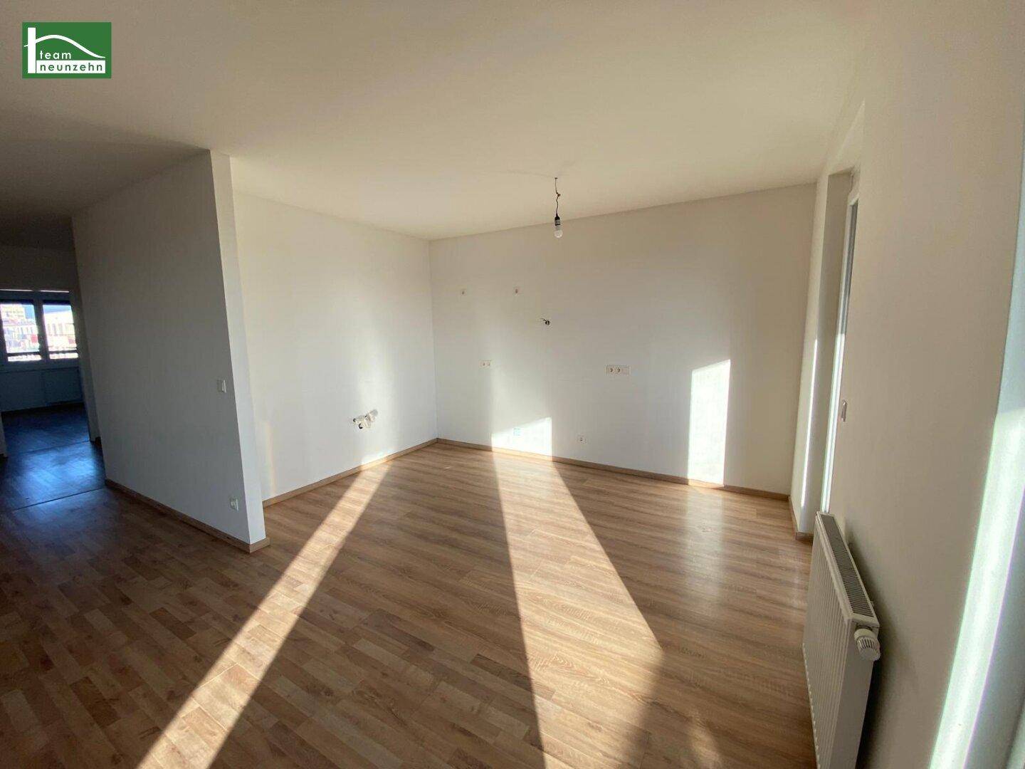 Heller, leerer Wohnbereich mit Laminatboden und viel Tageslicht, bereit zur Einrichtung.