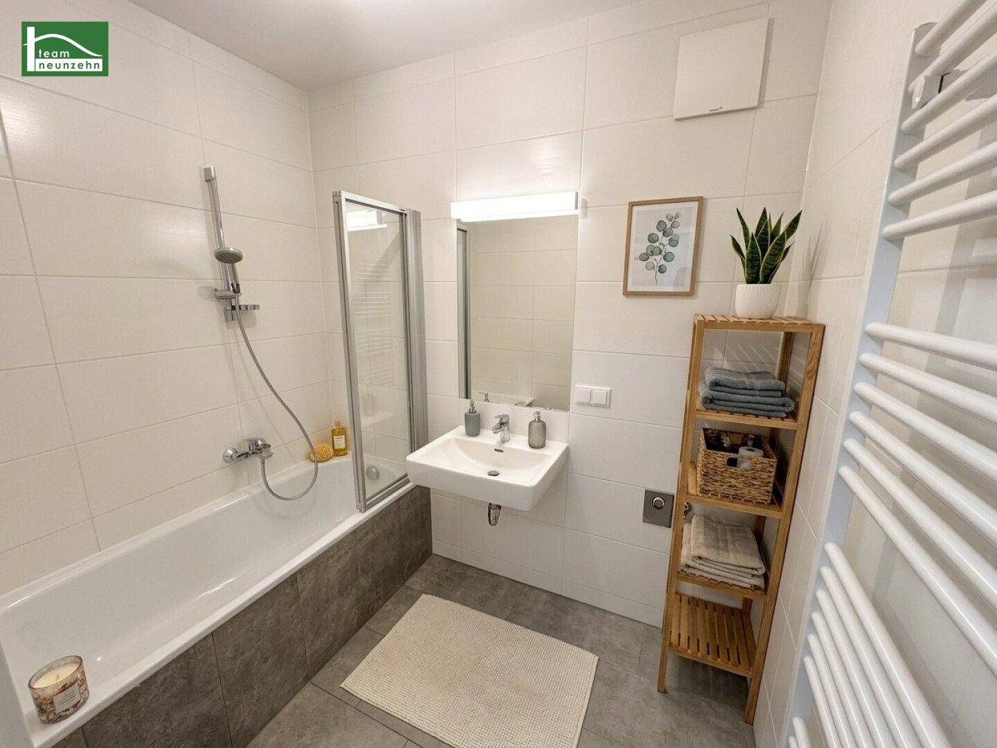 Modernes Badezimmer mit Badewanne, Duschabtrennung, Waschbecken und beheiztem Handtuchhalter.