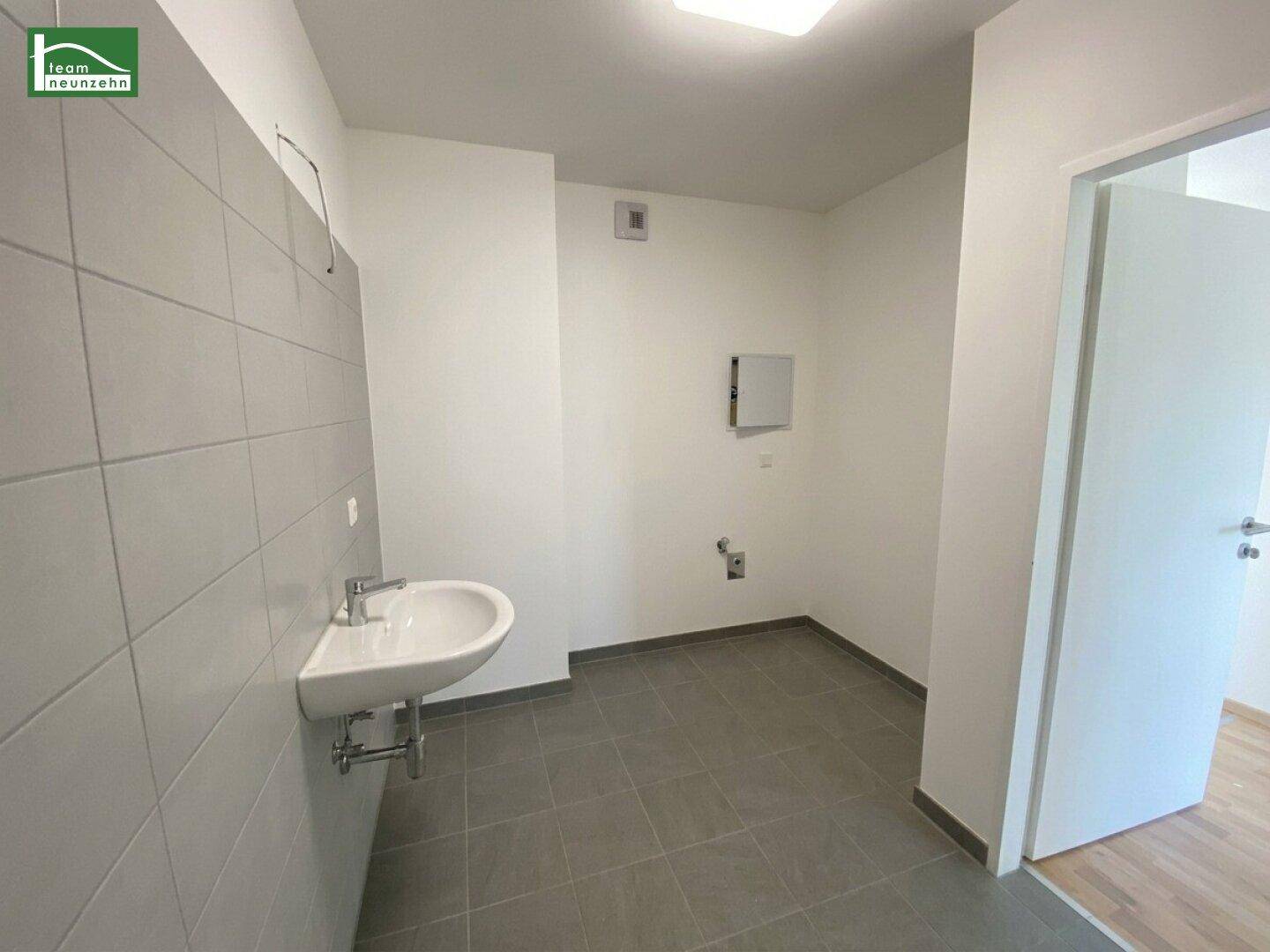 Badezimmer mit Waschbecken und grauen Fliesen, bereit für weitere Ausstattung und Gestaltung.