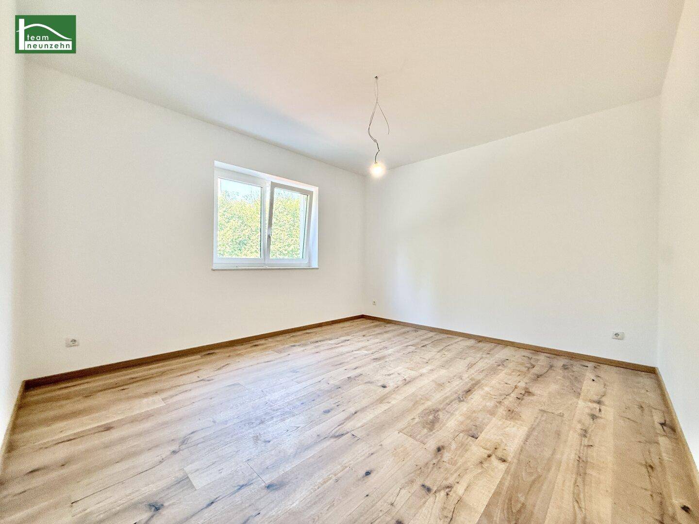 Leerer Raum mit hellem Holzboden und einem Fenster, bereit zur individuellen Gestaltung.