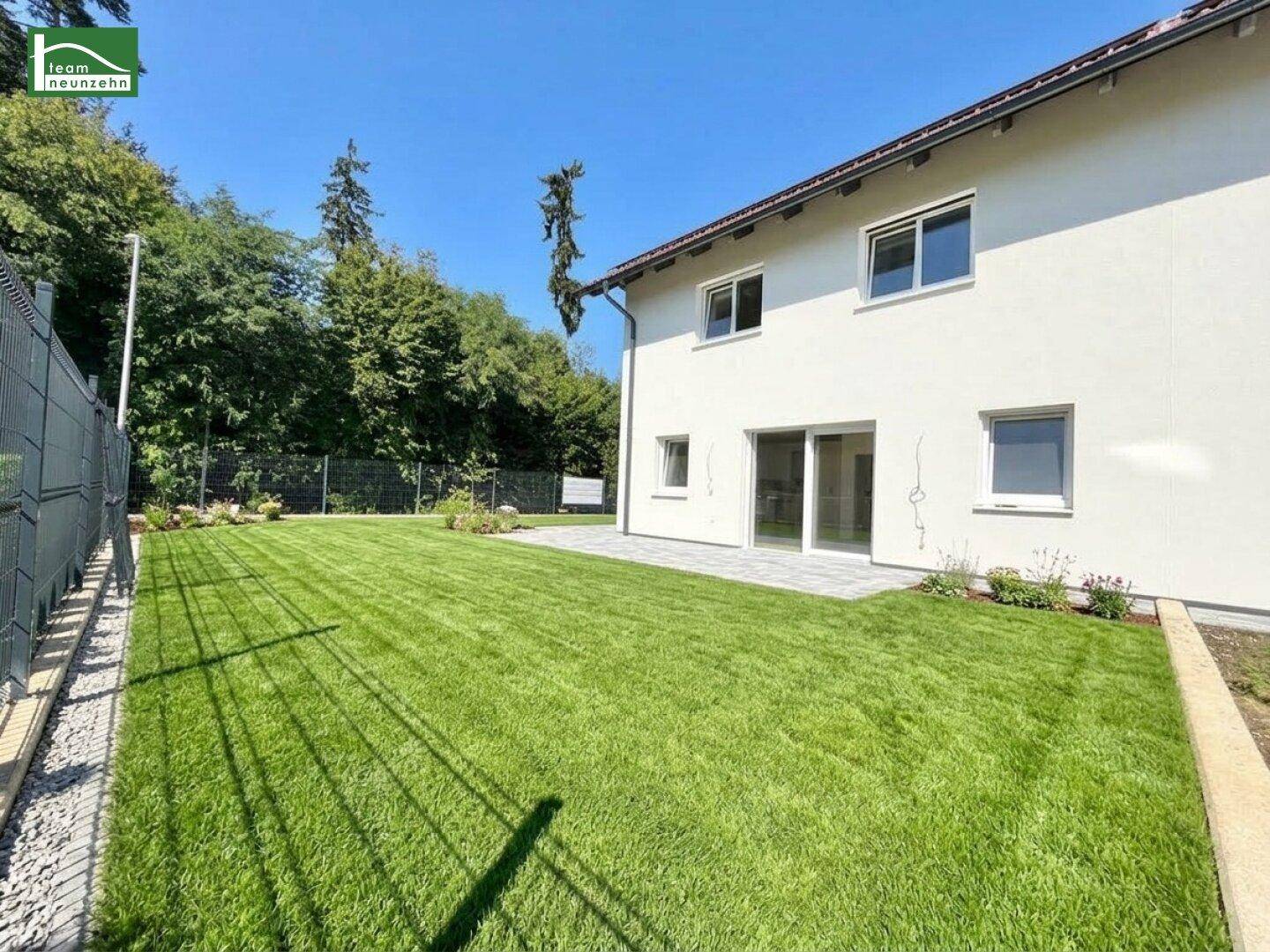 Gepflegter Gartenbereich mit großer Rasenfläche und Zugang zum Haus.
