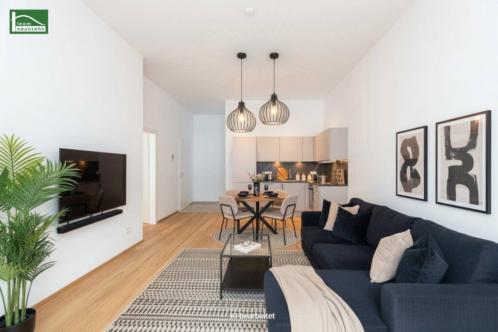 Heller offener Wohn- und Essbereich mit moderner Küche, dunklem Sofa und Holzboden.