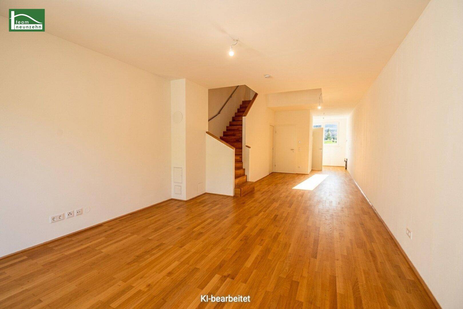 Offener Wohnbereich mit Holztreppe, viel Licht und Zugang zu weiteren Räumen.