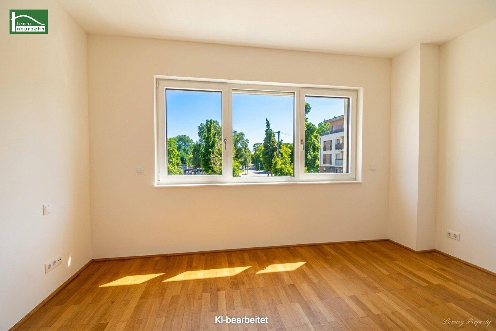 Helles Zimmer mit Holzboden und breitem Fenster mit Blick auf die Umgebung.