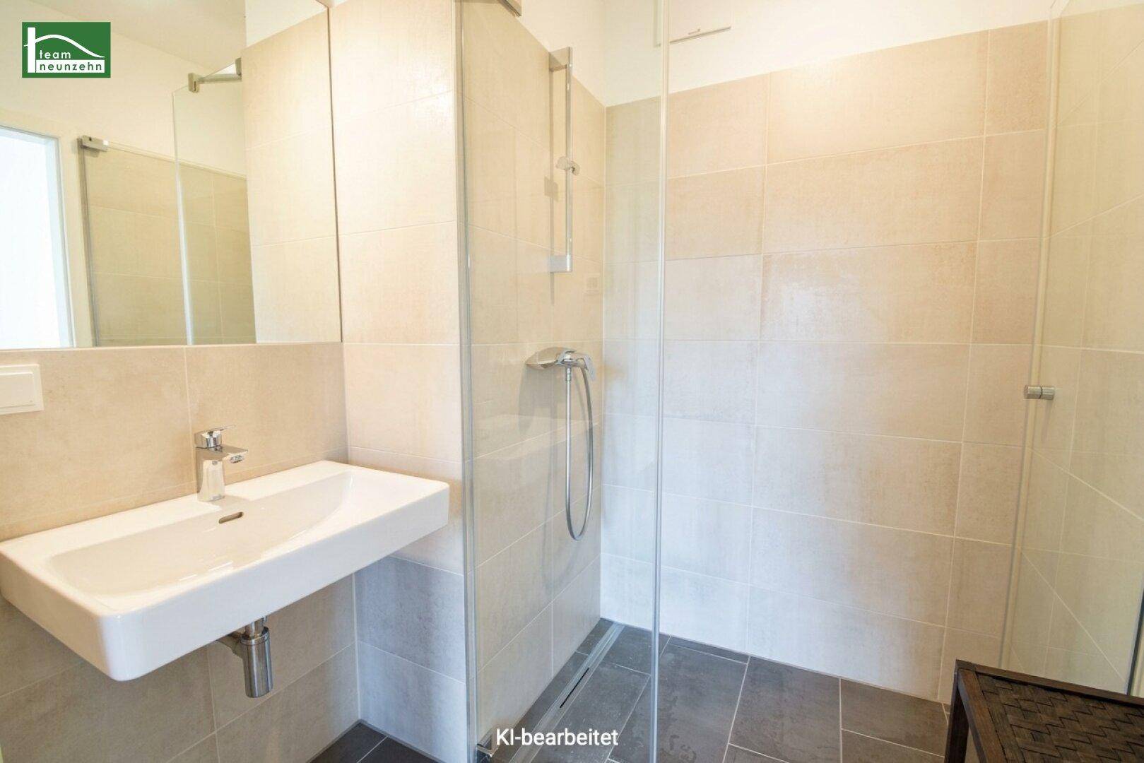 Modernes Badezimmer mit ebenerdiger Dusche, Waschbecken und beigefarbenen Fliesen.
